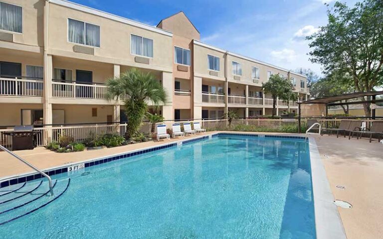 outdoor pool deck behind three story hotel at baymont by wyndham gainesville