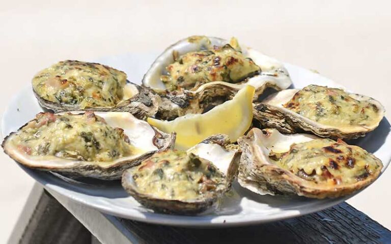 oysters rockefeller with lemon and beach background at runaway island panama city beach