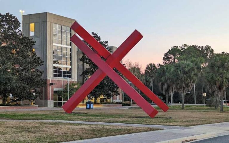 red steel beam sculpture with theater in background at curtis m phillips center for the performing arts gainesville