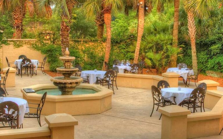 stone patio with dining seating and fountain at embers wood grill gainesville