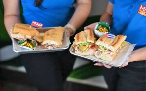 two servers holding sandwich trays at mi apa latin cafe gainesville