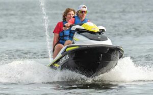 two teenage boys riding yellow jet ski through waves at adventures at sea panama city beach