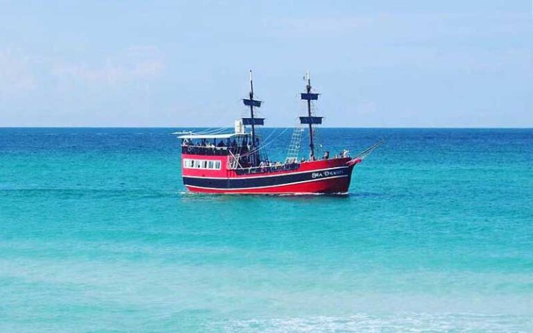 view across water of red and black galleon ship at sea dragon pirate cruise panama city beach