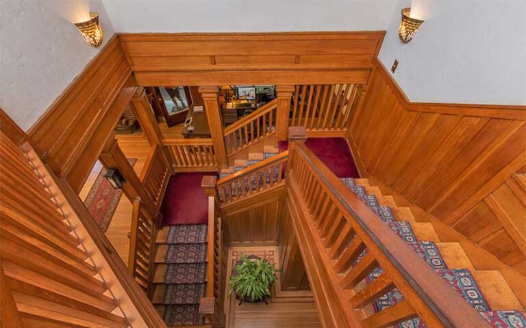 view looking down stairwell with carpeted wood craftsman stairs at herlong mansion micanopy gainesville