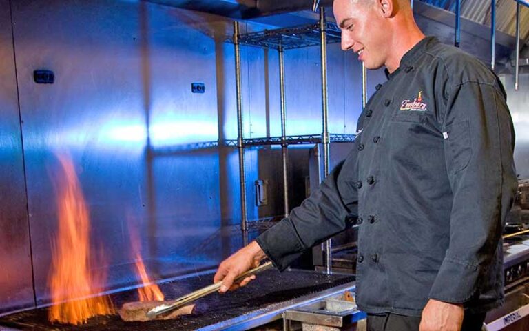 young chef turning steak on grill at embers wood grill gainesville