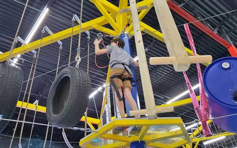 young person on ropes course with tires and blue barrel at flip factory zone gainesville