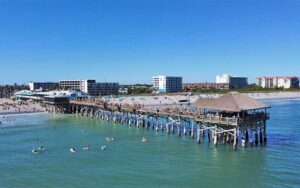 aerial view of beach with pier and surfers at cocoa beach space coast