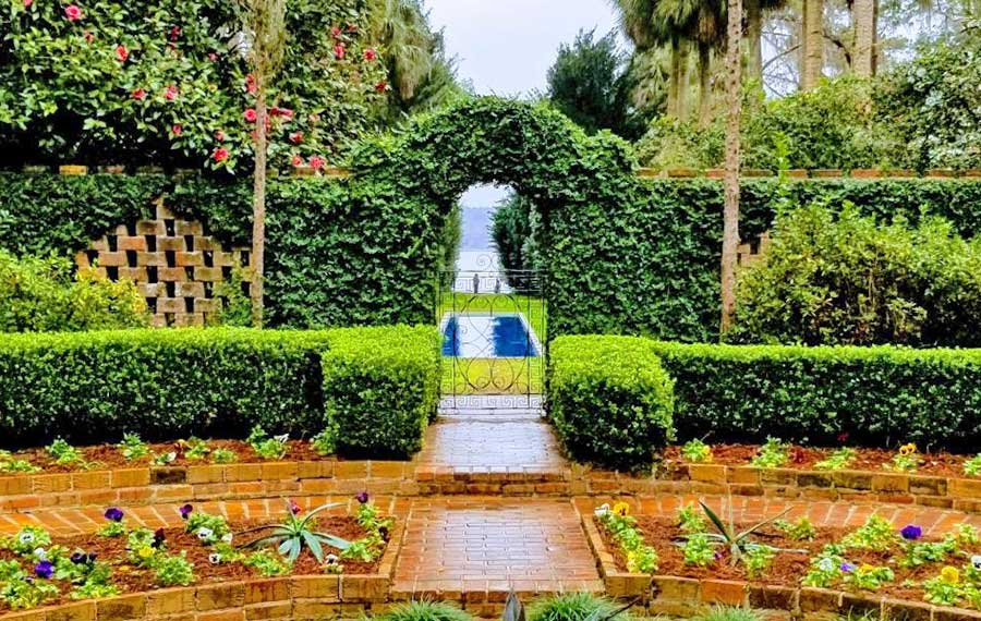 centerpiece garden with hedge wall and view through arched gate of pool at arthur b maclay gardens tallahassee