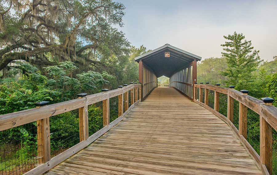 curving boardwalk with covered bridge over wooded area at lafayette heritage trail park tallahassee