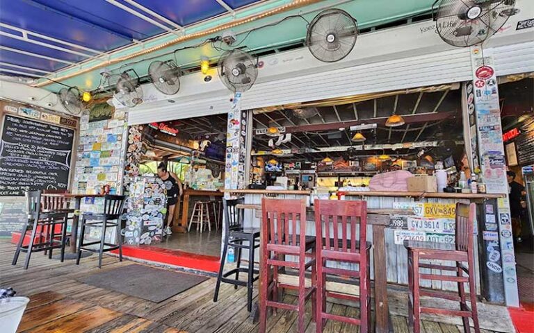 dock style bar with eclectic decor and red stools at hogfish bar grill key west