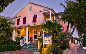 front evening exterior of pink victorian house with sign at louies backyard key west