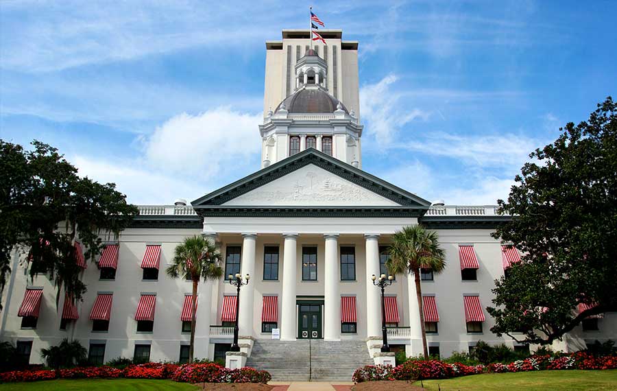 front exterior of capitol building with high rise in background and striped awnings at florida historic capitol museum tallahassee