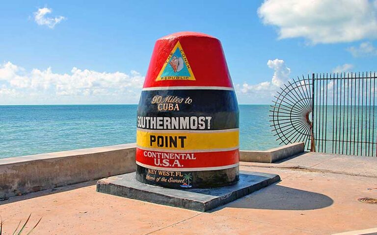 historic buoy marker with colorful lettering on edge of ocean with iron fence southernmost point of the continental usa key west