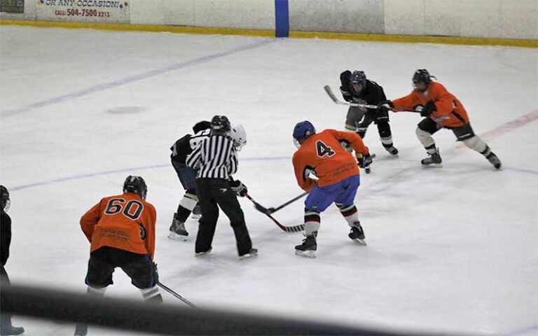 hockey players and referee facing off on ice at space coast iceplex rockledge