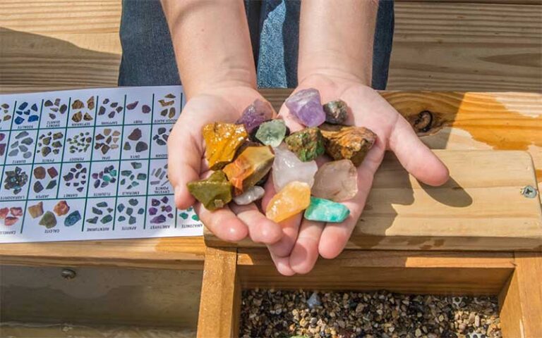 kids hands holding colorful gems over mining trough at gator n golf cape canaveral