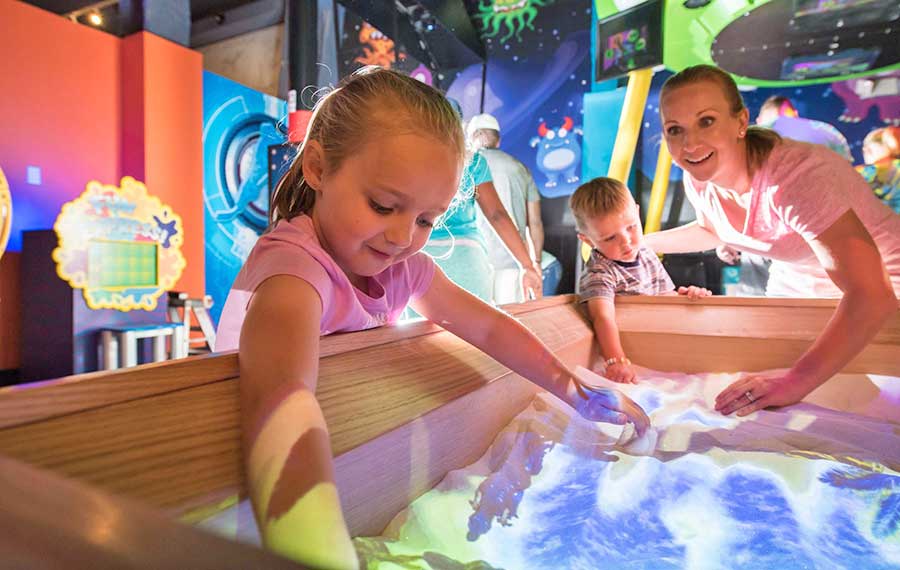 mom with kids interacting with sand in exhibit at wonderworks panama city beach