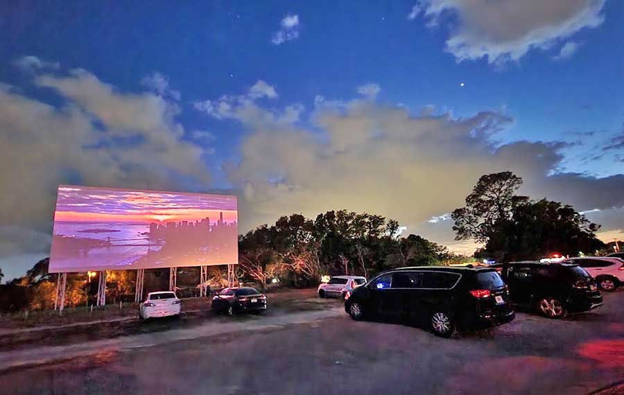 nighttime view of outdoor screen with movie and cars at silver moon drive in lakeland