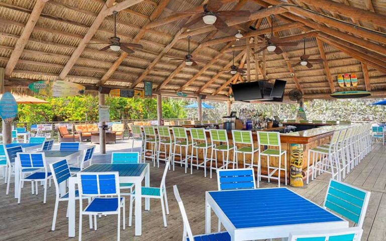 outdoor patio and bar under large thatched roof at longboards tiki beach grille cocoa beach