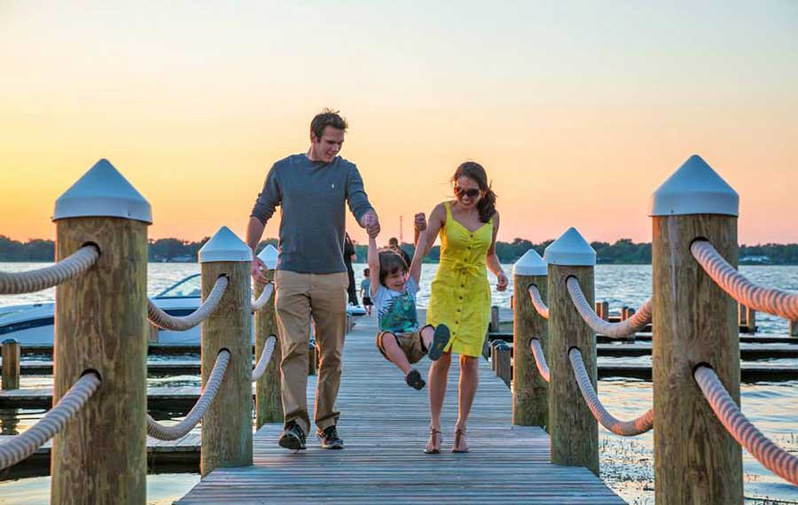 parents swinging child while walking along dock at sunset at harborside winter haven