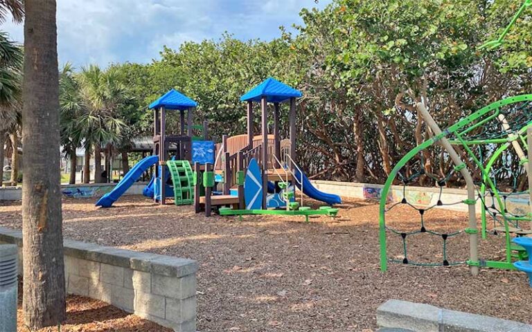 playground areas with low wall and trees at pelican beach park satellite beach