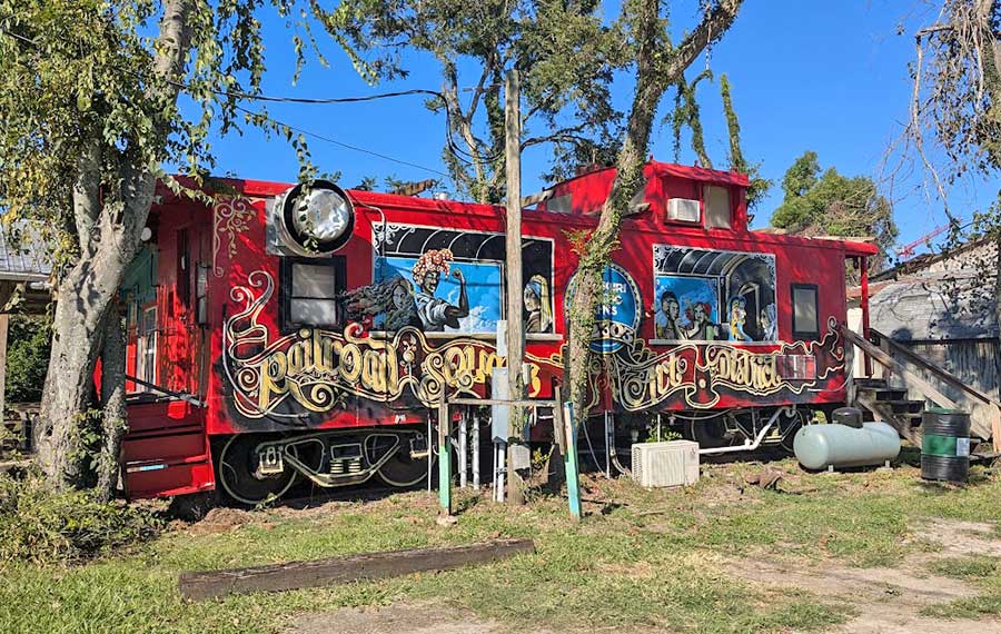 red caboose repurposed cafe with graffiti and trees at railroad square tallahassee