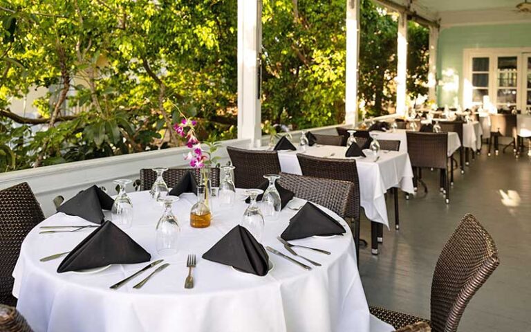 row of tables dining settings on outdoor porch at bagatelle key west