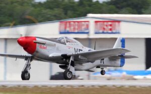 single engine military plane flying over runway at valiant air command warbird museum space coast