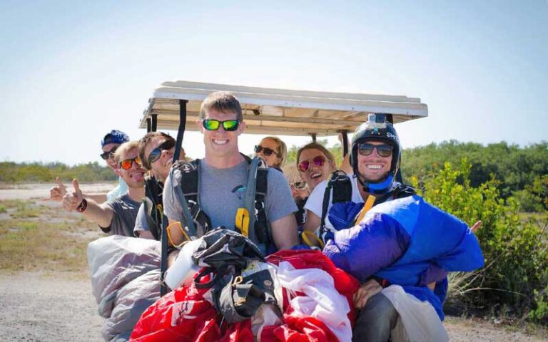 skydivers smiling riding golf cart with chutes balled up at skydive key west