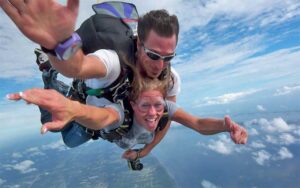 tandem man and woman smiling while flying over aerial of coastline at skydiving space center titusville