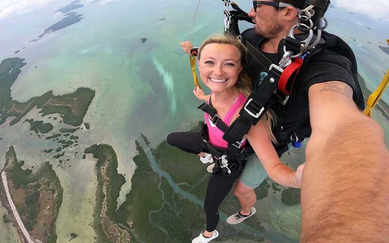 tandem skydiver with girl smiling under chute with ocean below at skydive key west