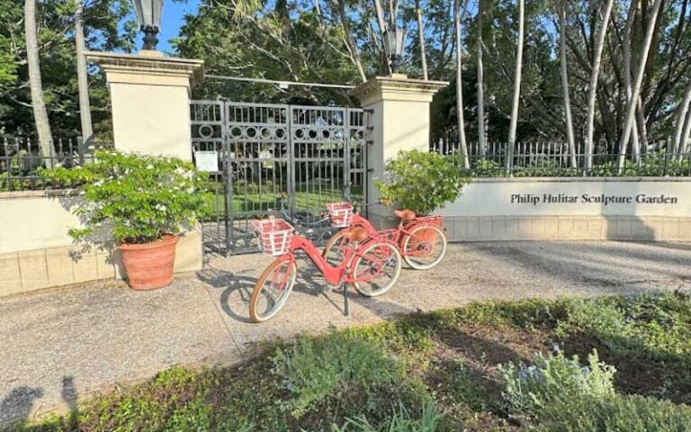 two ebikes at gate entrance to sculpture gardens at palm beach ebike rentals west