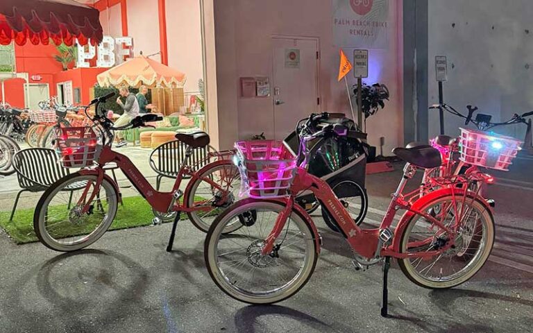 two ebikes in front of night exterior shop at palm beach ebike rentals west