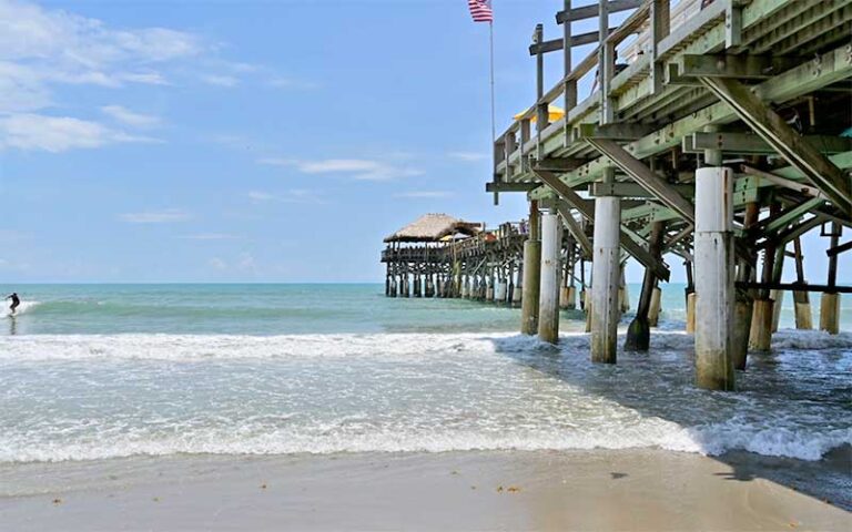 view from below pier with surfer and ocean at cocoa beach space coast