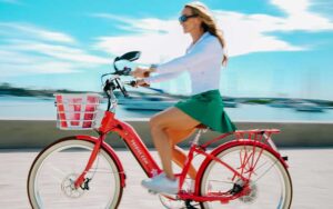 woman on electric bicycle speeding along waterfront at palm beach ebike rentals west