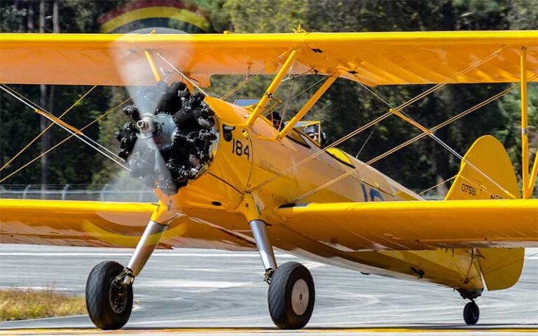 yellow airplane with spinning propeller on runway at valiant air command warbird museum space coast