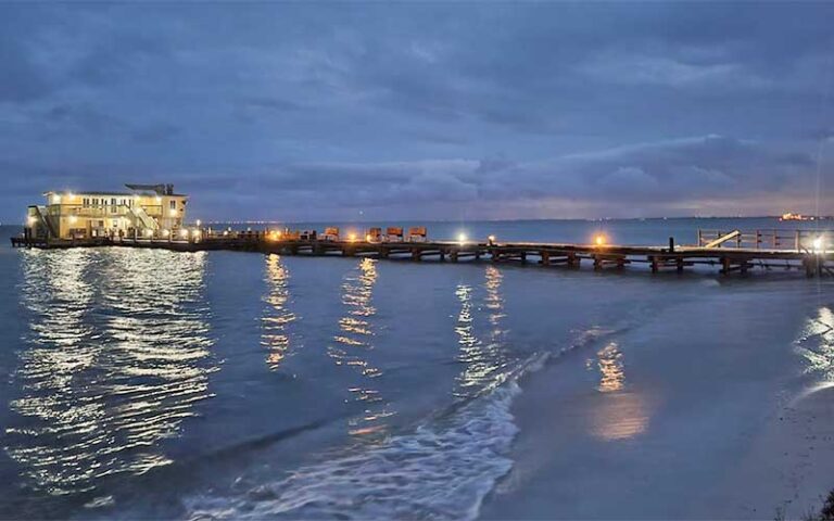 beach with pier and lighted diner at night at rod reel pier anna maria island