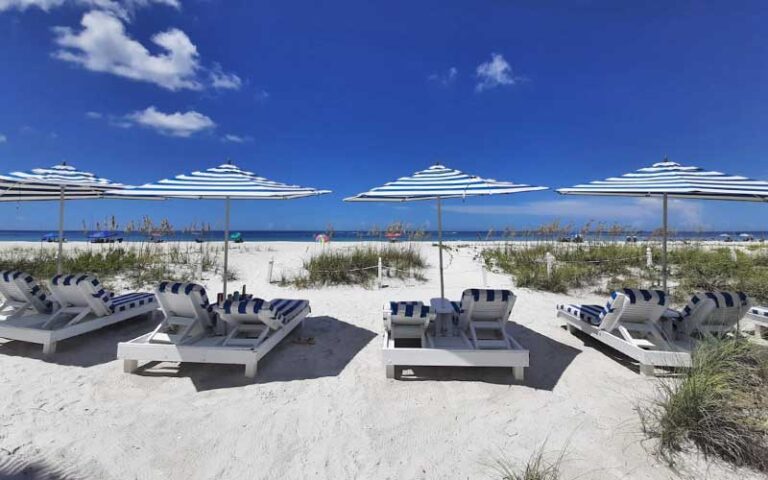 beach with striped loungers and umbrellas at bungalow beach resort bradenton anna maria island