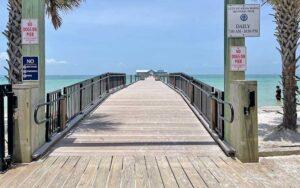 entrance to pier with signs and building in distance at anna maria city pier island