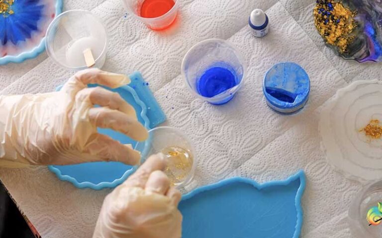 gloved hands making resin coasters in molds at fragments art studio kissimmee