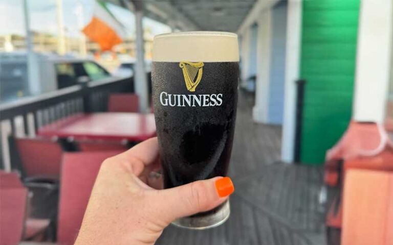 hand holding up guinness pint at freckled fin irish pub holmes beach anna maria island