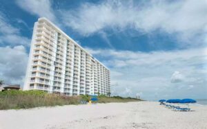 high rise hotel view from beach with loungers at radisson suite hotel oceanfront melbourne beach